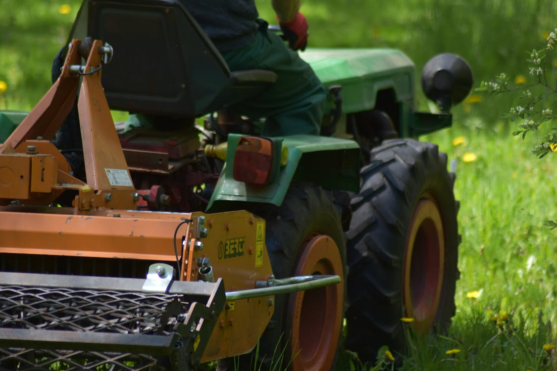 Tractor with lawn care equipment on green grass