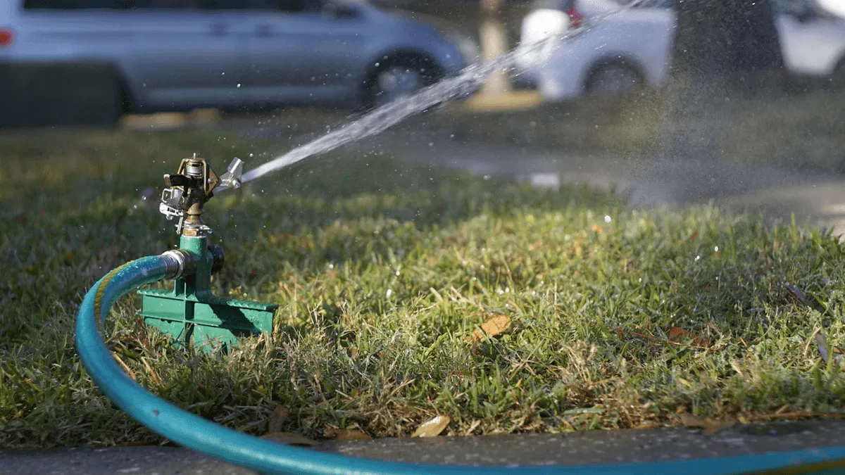 Lawn sprinkler watering grass on a sunny day